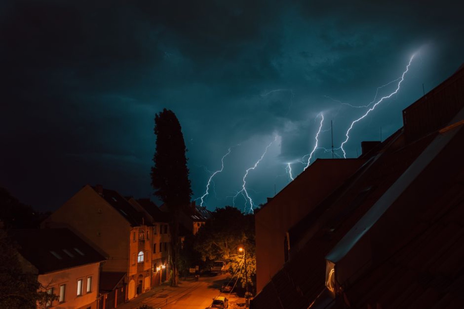 Lightning storm over residential neighborhood showing the power surges and outages that make voltage regulation critical