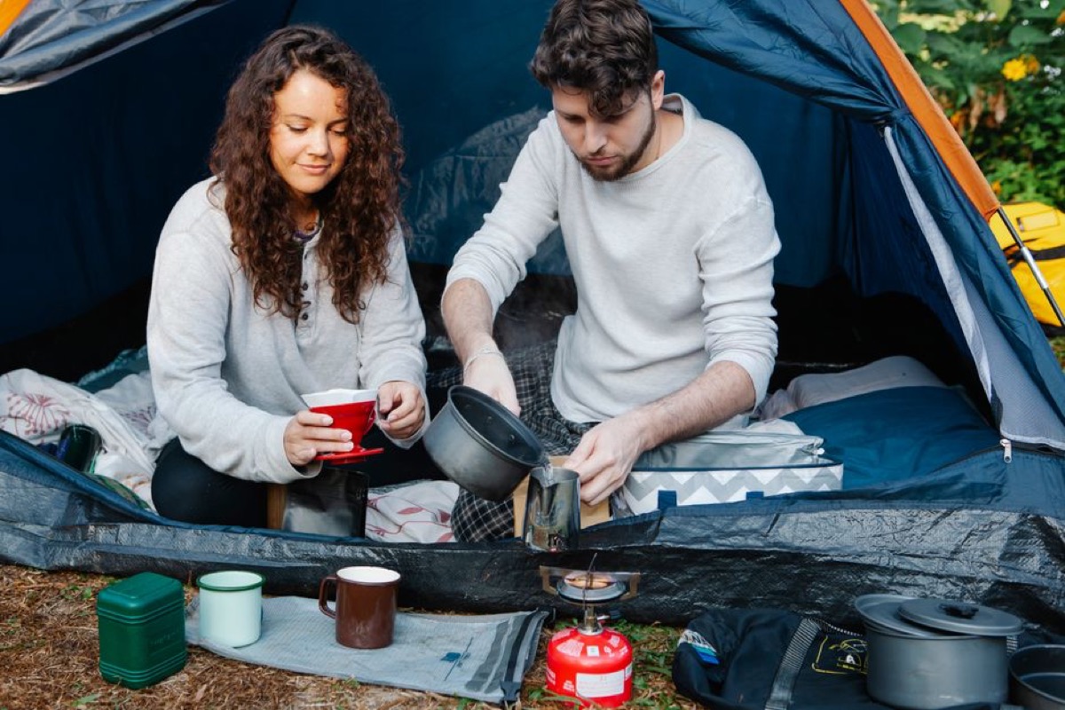 Camping scene showing tent and outdoor gear in natural wilderness setting requiring portable power solutions