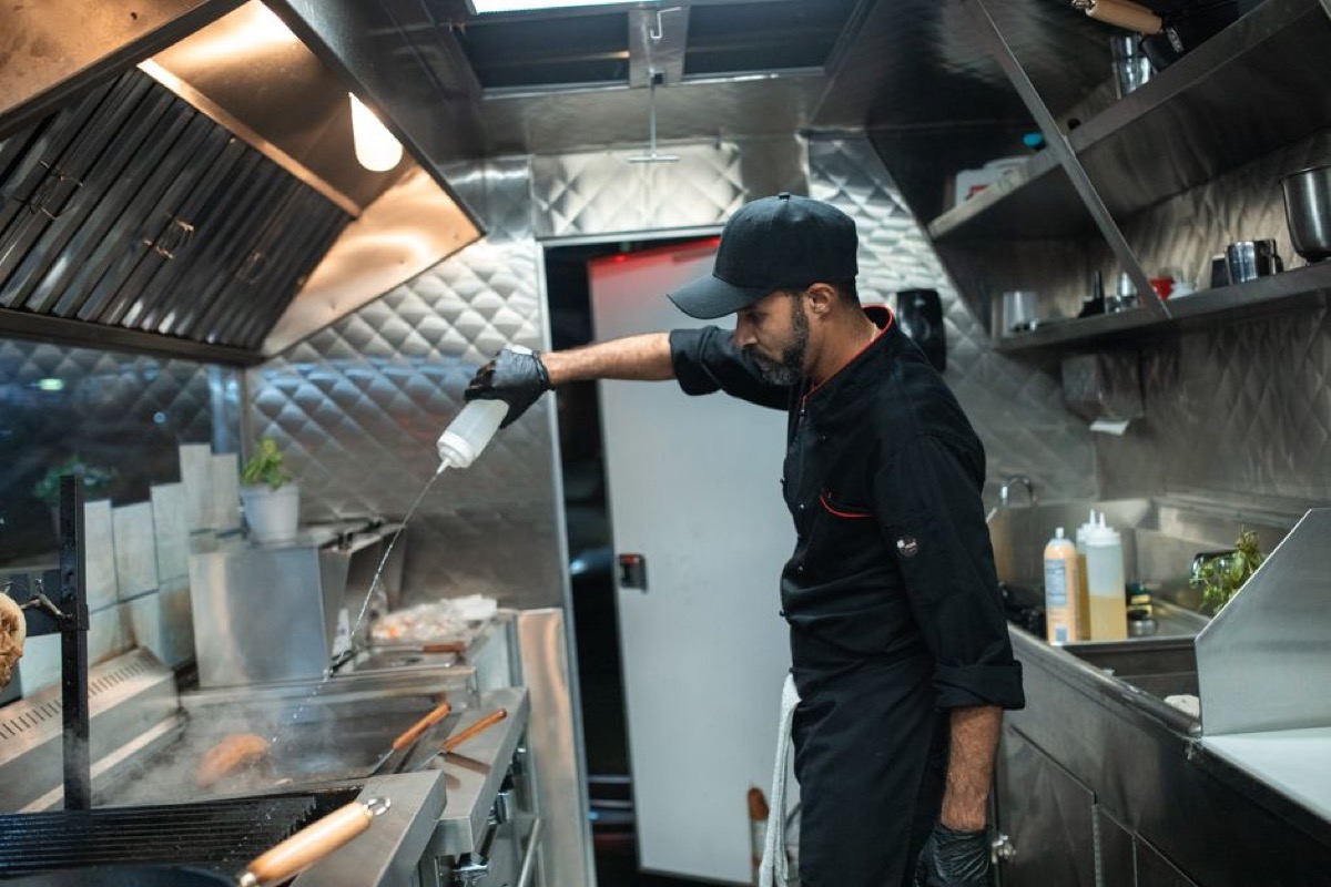 Commercial kitchen chef preparing food with multiple high-wattage appliances running simultaneously during service