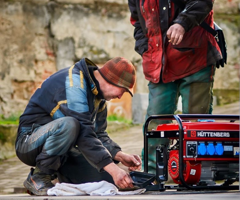 Technician performing maintenance on a red power generator, showing professional service requirements