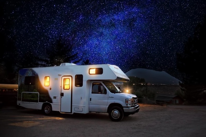 RV camper nighttime camping with exterior lights illuminated showing generator power in use